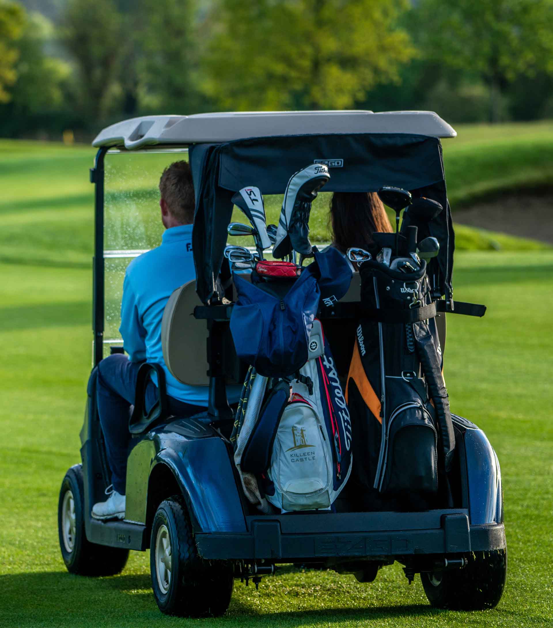 two golfers driving a golf cart.
